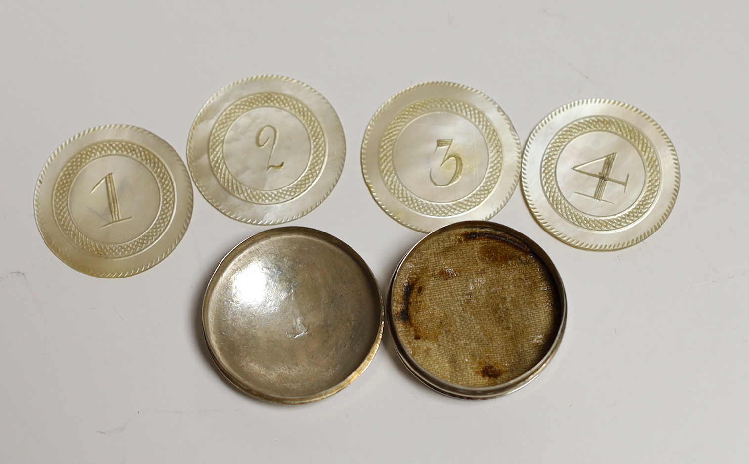 An early 19th century white metal counter box, 25mm, containing four counter numbered 1 to 4.